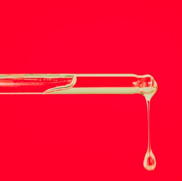 Glass pipette with drop of essential oil on red background. Trendy products of the year. Health and wellness concept. Cosmetic banner with copy space close up of glass pipette with drop of essential oil or face serum on red background trendy products of the year health and wellness concept cosmetic banner with copy space