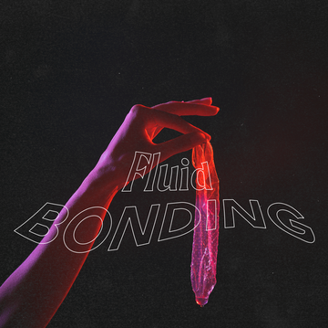 a hand holds a used condom against a black background